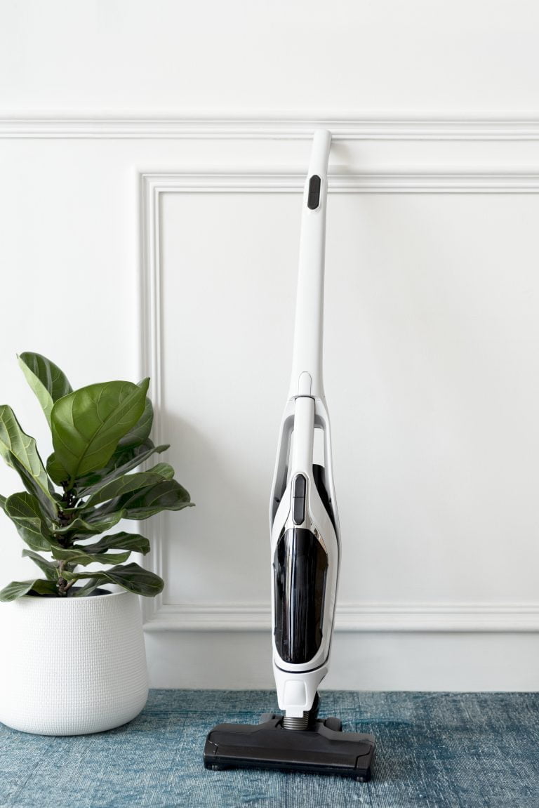 White handheld vacuum cleaner leaning against a wall